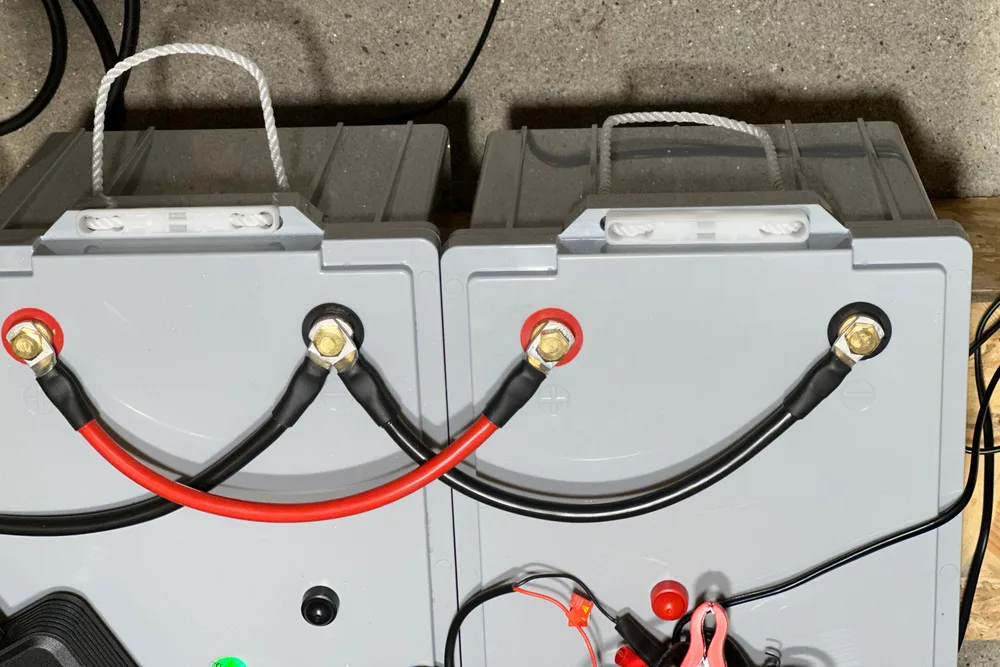 Zwei Batterien nebeneinander, mit einem roten und einem schwarzen Verbindungskabel parallel geschaltet