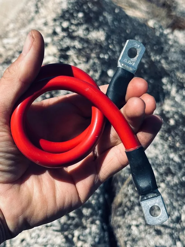 Rotes Batteriekabel 35 mm² eng zu einer Schlaufe gebogen in einer Hand,
         der Rohrkabelschuh trägt die eingeprägte Kennzeichnung KL 35/8