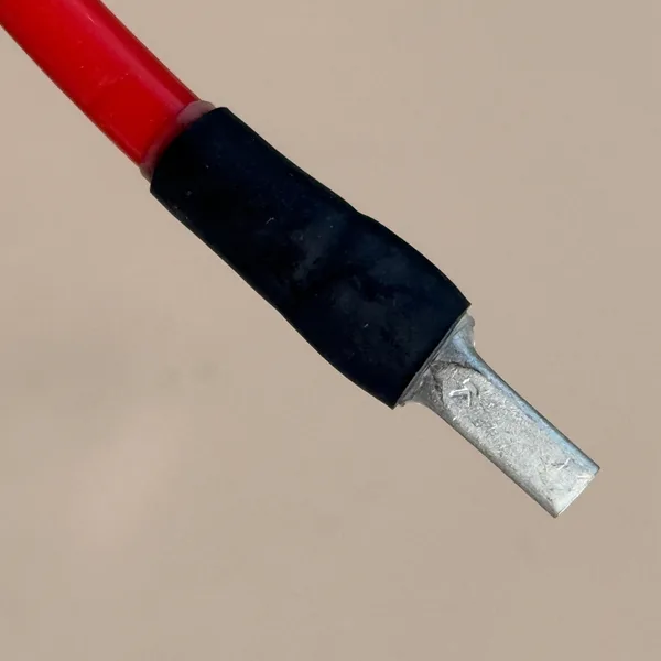 Rotes Batteriekabel mit verpresstem Stiftkabelschuh, der Übergang unter schwarzem Schrumpfschlauch