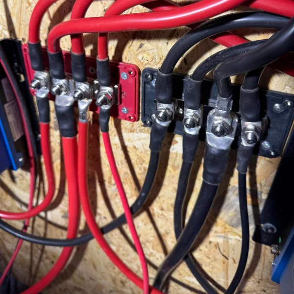 Verteilerblock mit vielen roten und schwarzen Batteriekabeln, jedes Ende mit Rohrkabelschuh und Schrumpfschlauch