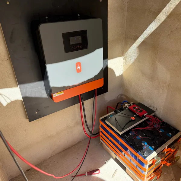 Wechselrichter an einer Wand, darunter ein Batterieblock aus Lithiumzellen in einem Technikraum