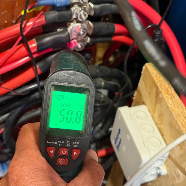 Infrarotthermometer in der Hand, auf verschraubte Kabelschuhe gerichtet, die Anzeige zeigt 50,8 Grad
