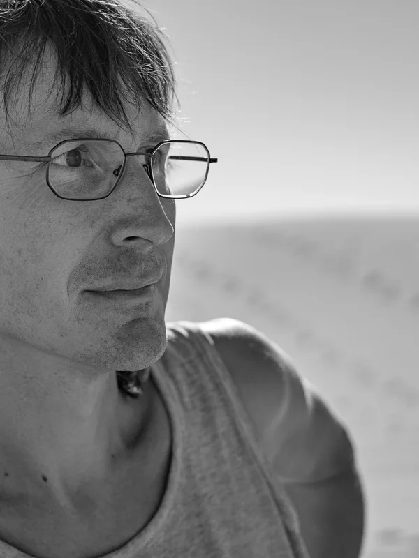 Black-and-white portrait of André Bonsch wearing glasses, taken
         outdoors